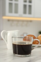 Aromatic coffee in glass cup on white marble table, space for text