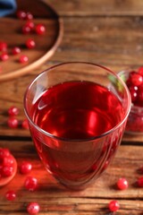 Tasty cranberry juice in glass and fresh berries on wooden table, closeup