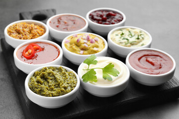 Different tasty sauces in bowls on grey table, closeup