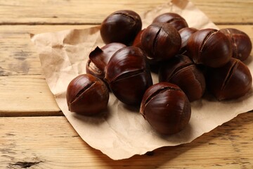 Fresh edible sweet chestnuts on wooden table, closeup