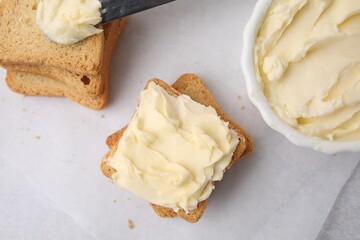 Slices of bread with tasty butter on light table, flat lay