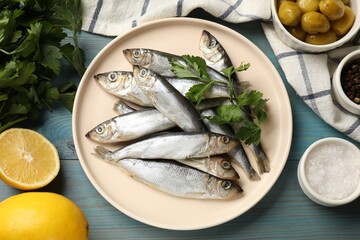 Fresh raw sprats, parsley and other products on light blue wooden table, flat lay - obrazy, fototapety, plakaty