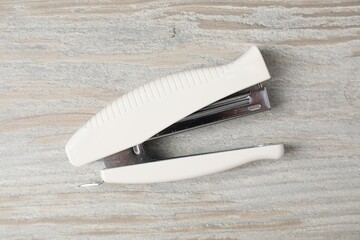 One white stapler on wooden table, top view
