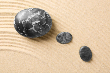 Fototapeta na wymiar Zen garden stones on beige sand with pattern, flat lay