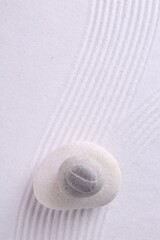 Zen garden stones on white sand with pattern, top view. Space for text