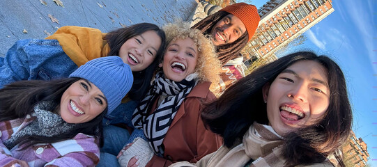 Multicultural best friends having fun taking group selfie portrait outside. Smiling guys and girls celebrating party day hanging out together on city street. Happy lifestyle and friendship concept.