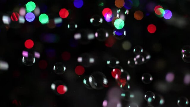 Garlands and soap bubbles in the dark. Many colored blurred lights in the background. Festive atmosphere, soap bubbles are flying everywhere. Christmas atmosphere