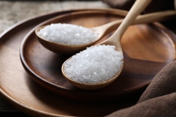 Fototapeta na wymiar Organic salt in spoons on wooden table, closeup