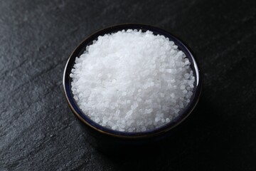 Organic white salt in bowl on black table