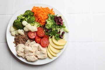 Balanced diet and healthy foods. Plate with different delicious products on white tiled table, top view. Space for text