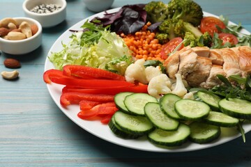 Balanced diet and healthy foods. Plate with different delicious products on light blue wooden table, closeup