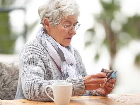 Elderly Woman, Coffee And Card Games At Table On Bokeh Background For Retirement, Old Age And Idea. Senior Person Or Grandma With Deck In Hand For Thinking, Playing Poker And Relax Or Hobby Outdoors