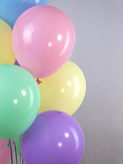 Fountain of pastel colored balloons on a gray background, half frame