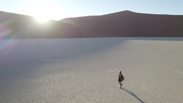 Girl walking on the bottom of a dried up lake in the Namib Desert, Deadvlei