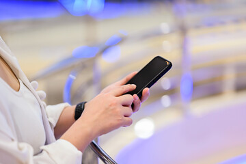 A cropped shot of an Asian woman using her smartphone, reading online articles, or responding to messages while sitting at a cafe in the city.