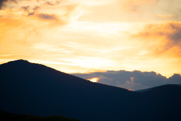 Sunset in the mountains. Silhouettes of fir trees on a mountainside in the sunset light. dark evening photo