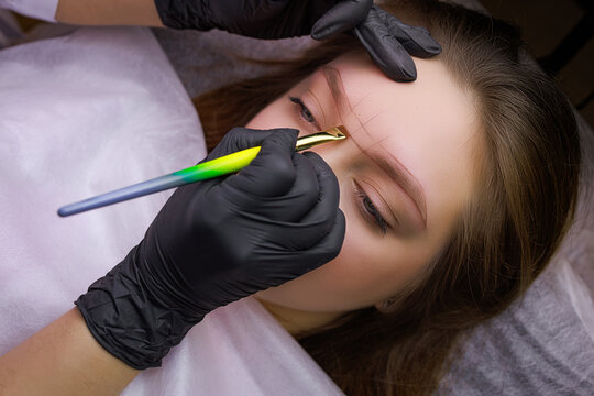 The hands of the master who makes a mark on the model's eyebrows before the permanent makeup procedure. PMU Procedure, Permanent Eyebrow Makeup.