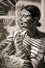 Fototapeta na wymiar Black and white portrait of a girl. Shadows on the girl from palm leaves