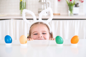cute little girl in rabbit ears on head playing egg hunting for Easter. celebrate Easter at home.