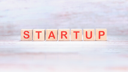 Startup - word concept on building blocks, text, letters on wooden cubes on a light background