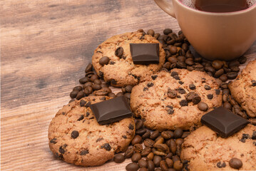 There are craft chocolate cookies and a cup of coffee on an old wooden background. View from above