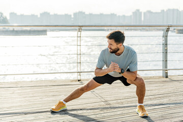 Man stretching on a sunny waterfront boardwalk, fitness routine in the city.