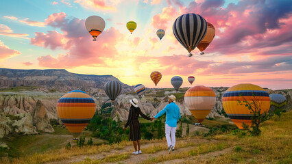 Kapadokya Cappadocia Turkey, a happy young couple during sunrise watching the hot air balloons of...