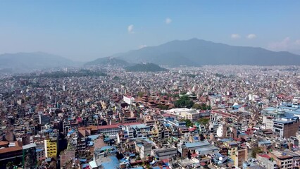 Aerial view of Kathmandu city, Nepal, showcasing the densely packed buildings and the majestic Himalayan mountains in the background.