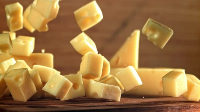 Super slow motion pieces of cheese fall onto a cutting board. Filmed on a high-speed camera at 1000 fps. High quality FullHD footage