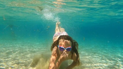 Child swimming underwater in a blue sea