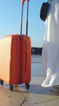 Young Woman with the Orange Suitcase on the travel. Female feet and luggage going on holiday and close up travel.
