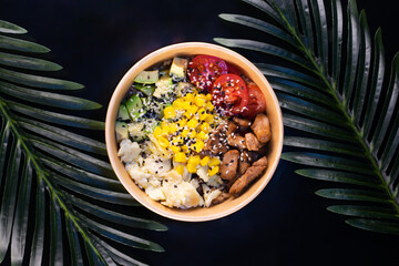 bowl with chicken and vegetables in disposable dishes on a dark background