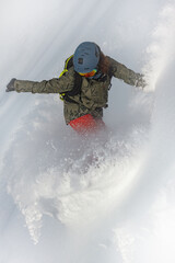 Powder snowboarding. Freeride snowboarder girl riding off-trail fresh powder snow high in the...