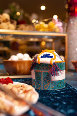 Yurt-shaped Container with Traditional Patterns on Blue Tablecloth, Surrounded by Sweets and Nuts