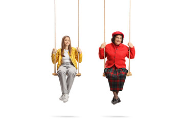 Teenage girl and an elderly lady sitting on wooden swings