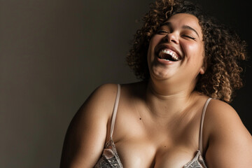 dynamic studio portrait of a plus size woman in fashionable underwear laughing and enjoying the moment surrounded by soft flattering lighting that highlights her confidence