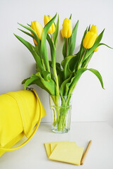 Yellow tulips next to yellow stickers and a yellow bag on a white background