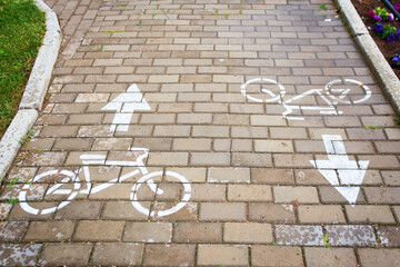 A brick walkway adorned with bicycles and arrows painted on the surface, creating a charming and unique path for pedestrians to enjoy - Powered by Adobe