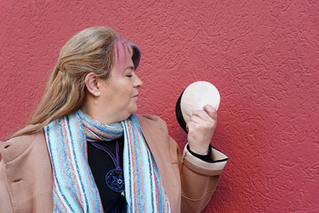 Smiling woman holding two colors stoma bags on red background. World Cancer Day