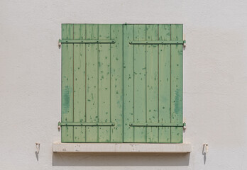 Close-up of a window closed with pale green shutters on  white wall background
