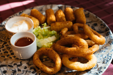 Deep fried onion rings and crispy potato croquettes with mayonnaise sauce and ketchup