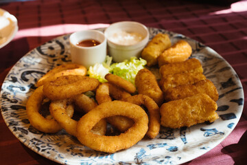 Deep fried onion rings and crispy potato croquettes with mayonnaise sauce and ketchup