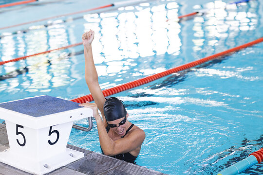 A swimmer celebrates victory at the poolside, with copy space