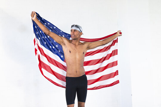 Young biracial male athlete swimmer holds an American flag with pride