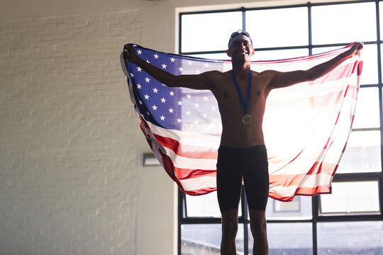 Young biracial male athlete swimmer celebrates a victory, with copy space