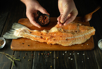 The cook hands season a fish carcass on a cutting board with spices. The concept of preparing a...