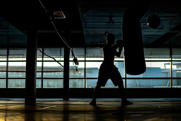 Silhouette photo of boxer training with punching bag in dark sports hall. Generative AI. - 744574100