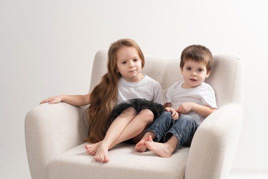 children a boy and a girl are sitting in an armchair in the studio, family
