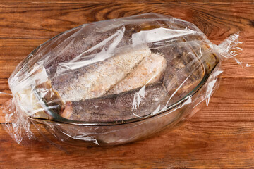Raw hake pieces in casserole pan placed in oven bag