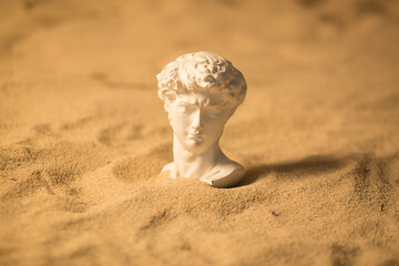 Bust of a man made of plaster, sculpture in the sand